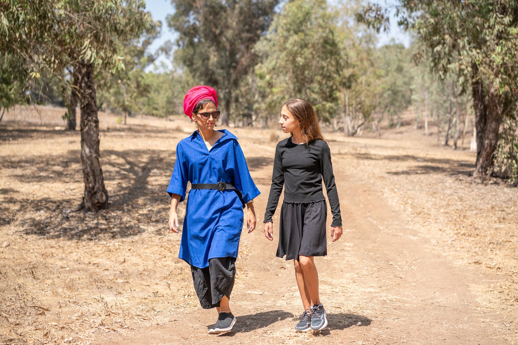רוני הולכת לצד נהגת בשביל עפר בחורשה